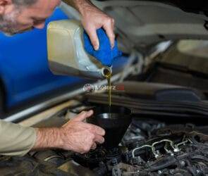 Mechanic pouring oil into car engine