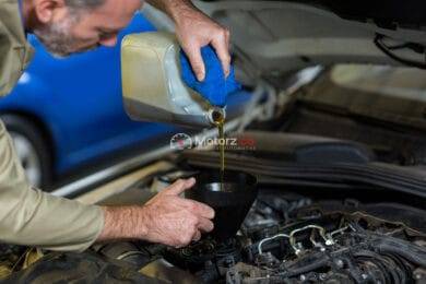 Mechanic pouring oil into car engine